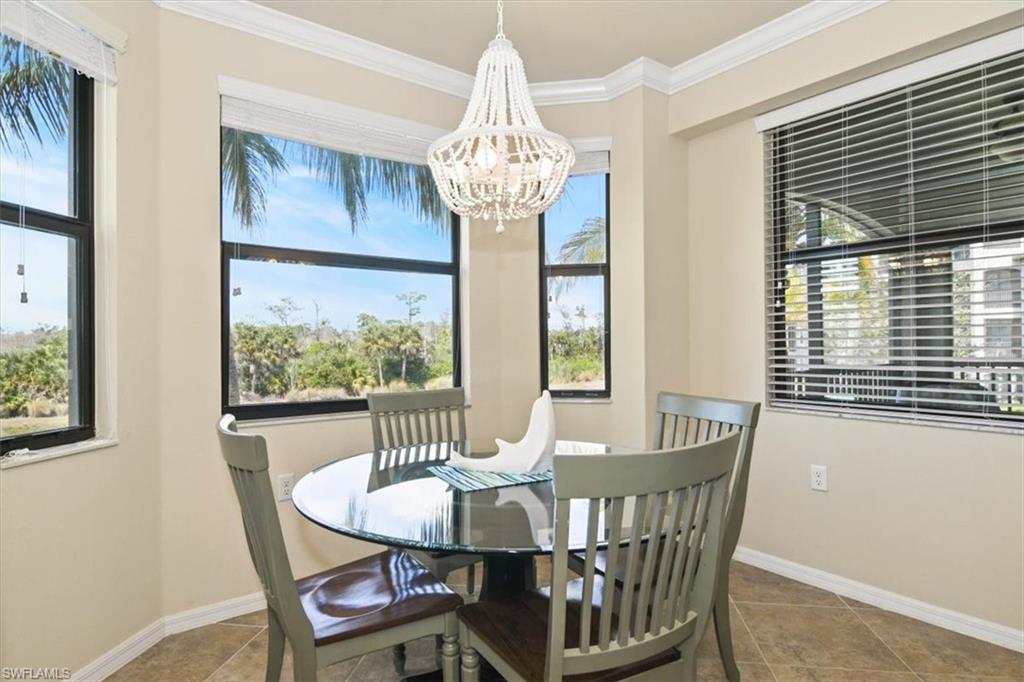 Dining area with ornamental molding, suspended lighting, plenty of natural light, and tile patterned floors