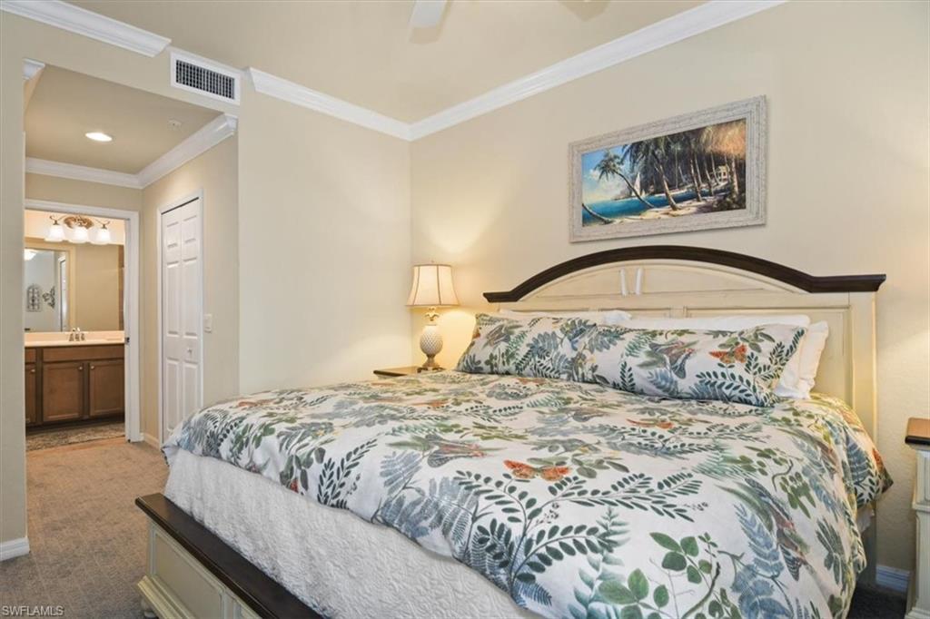 Bedroom featuring carpet, ornamental molding, a closet, ensuite bathroom, and a ceiling fan