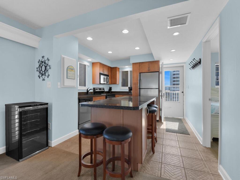 Kitchen with recessed lighting, a breakfast bar area, appliances with stainless steel finishes, a kitchen island, and wine cooler