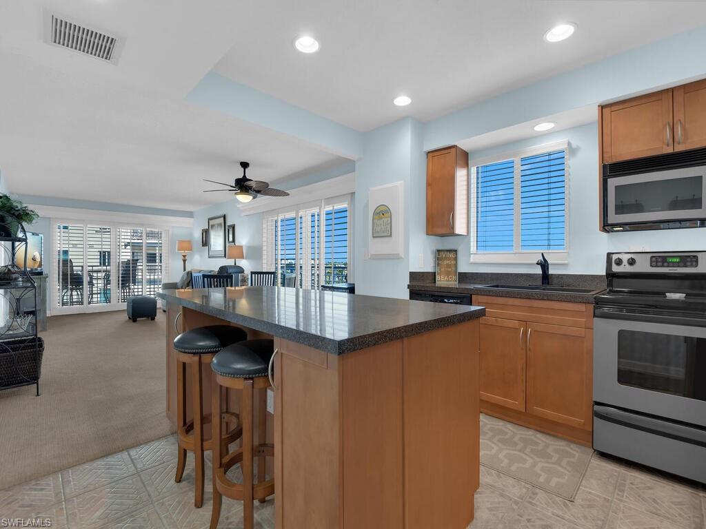 Kitchen with brown cabinetry, stainless steel appliances, open floor plan, a breakfast bar area, and recessed lighting