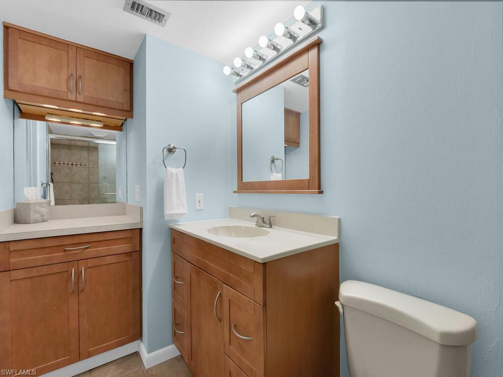 Bathroom with vanity, a tile shower, and light tile patterned floors