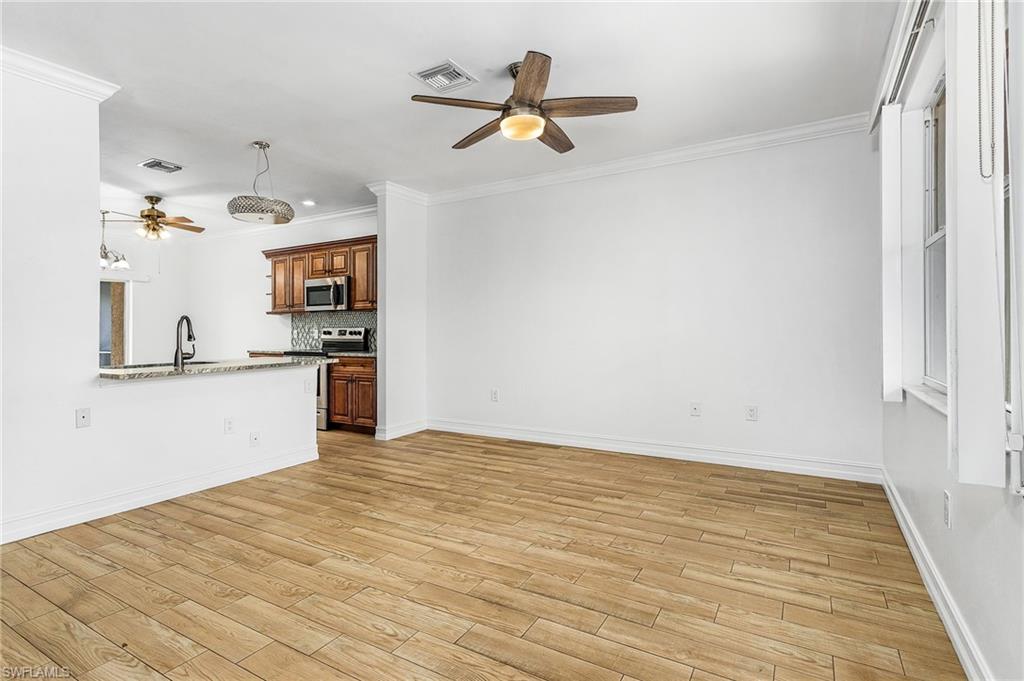 Unfurnished living room featuring ceiling fan, wood-style tiled floors