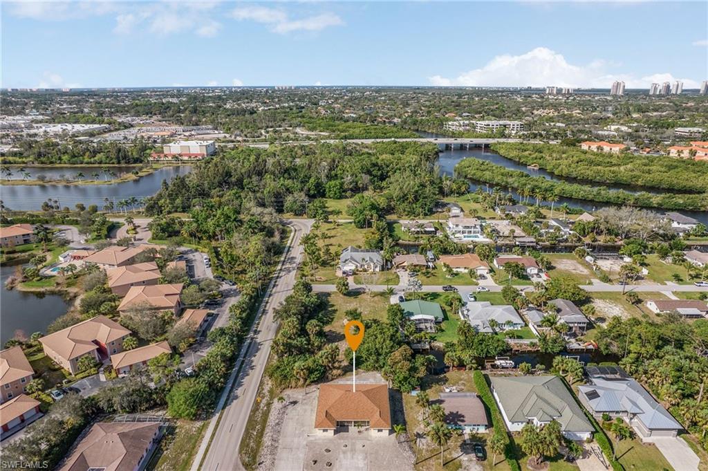 Aerial view of property and surrounding area featuring a nearby body of water and nearby suburban area
