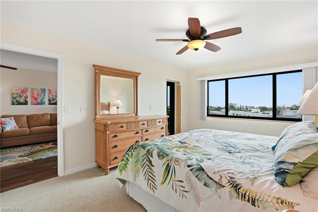 Primary bedroom with carpet floors and ceiling fan & door to patio - Virtually Edited Image
