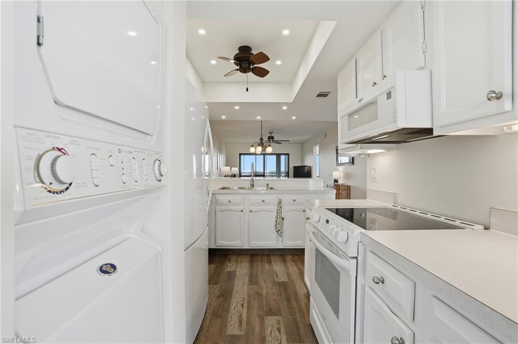Kitchen featuring white stove/microwave, white cabinetry, light countertops,, and a ceiling fan , in unit stackable washer/dryer- Virtually Edited Image