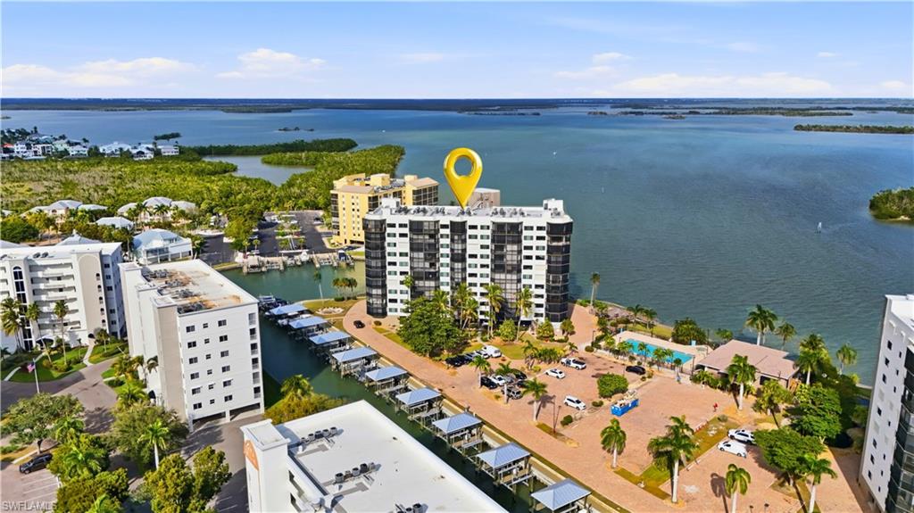 Aerial view of Pointe Estero showing Estero Bay with canal & boat docks/lifts. Pool and Clubhouse & parking on the right- Virtually Edited Image