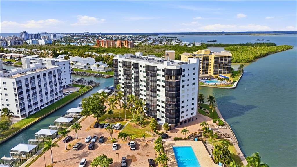 Aerial view featuring Estero Bay & canal with boat docks and Harbour Pointe, pool and parking, boat docks/lifts on canal- Virtually Edited Image