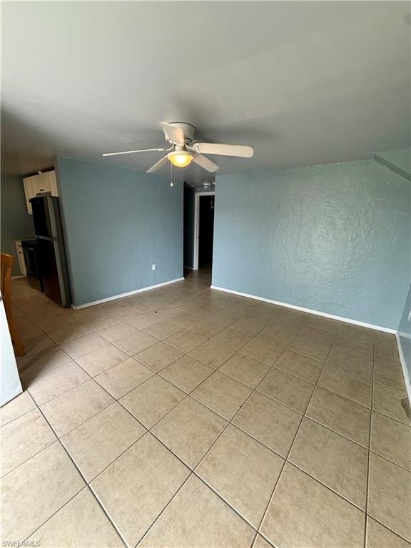 Unfurnished room with a textured wall, ceiling fan, and light tile patterned floors