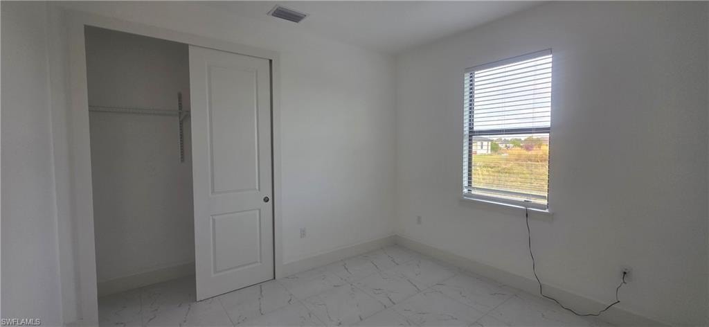 Unfurnished bedroom with light marble finish flooring and a closet