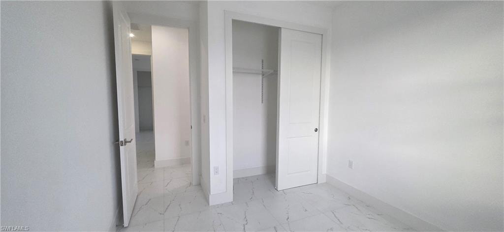 Unfurnished bedroom with light marble finish flooring and a closet