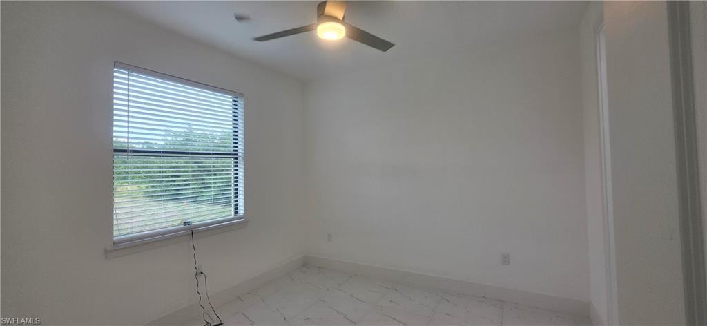 Unfurnished room featuring light marble finish floors and ceiling fan