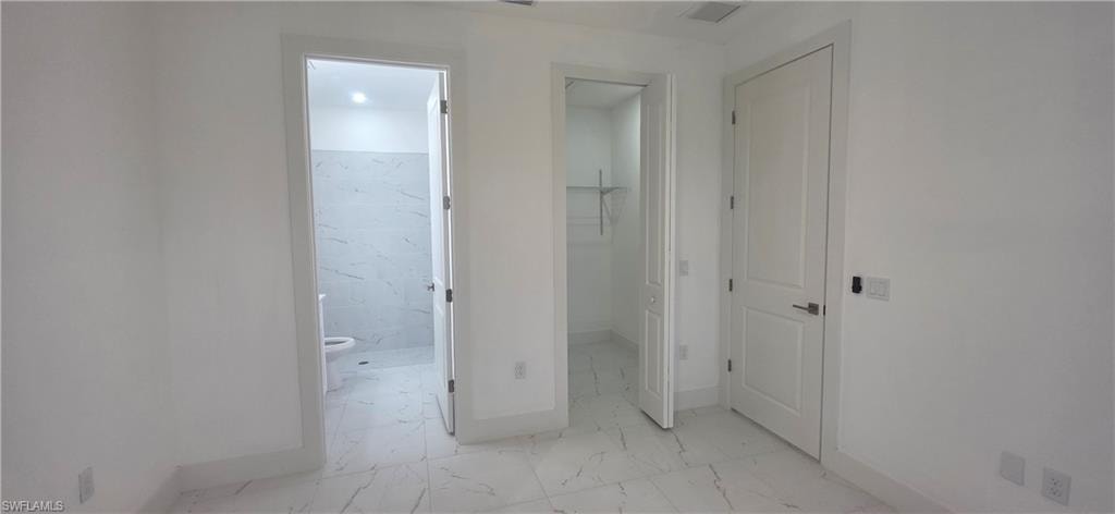 Hallway featuring light marble finish floors and baseboards