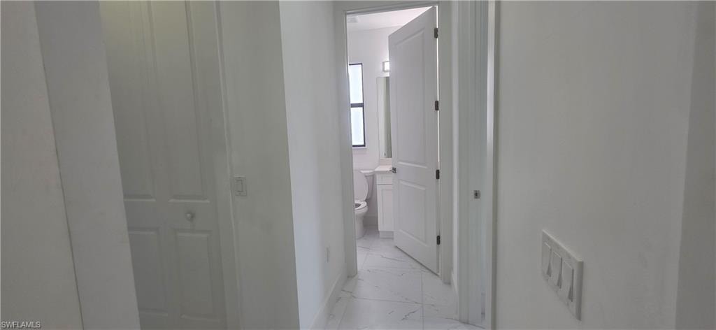 Corridor featuring light marble finish floors and baseboards