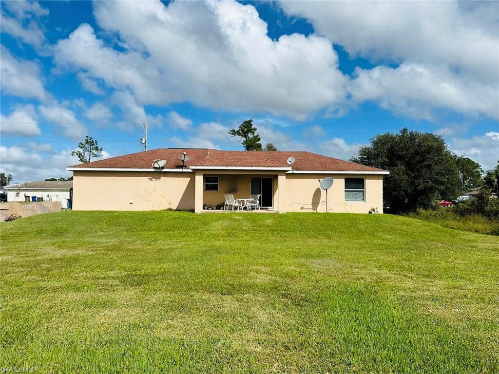Rear view of house with a patio, a lawn, and stucco siding