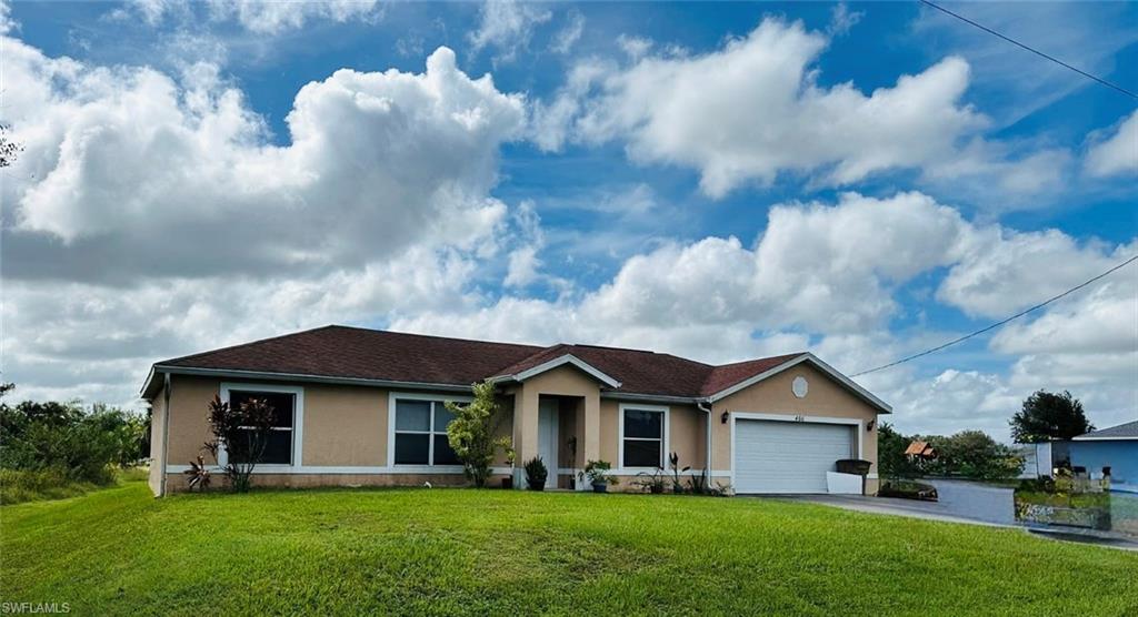 Ranch-style house with stucco siding, a front lawn, and driveway