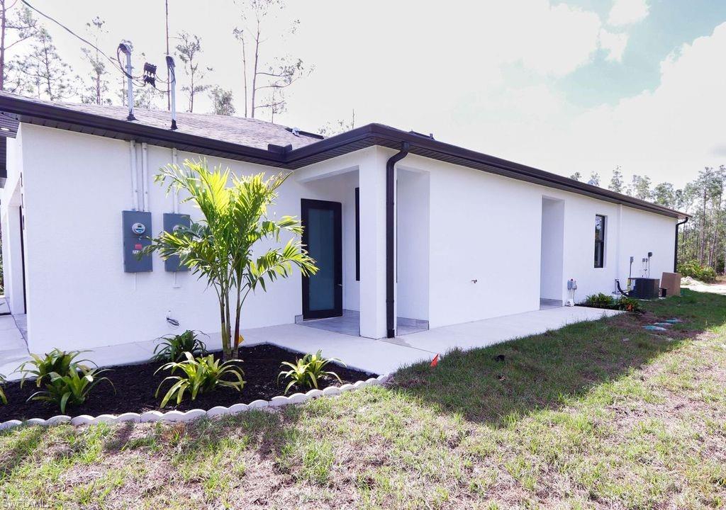 Back of house with stucco siding and a lawn