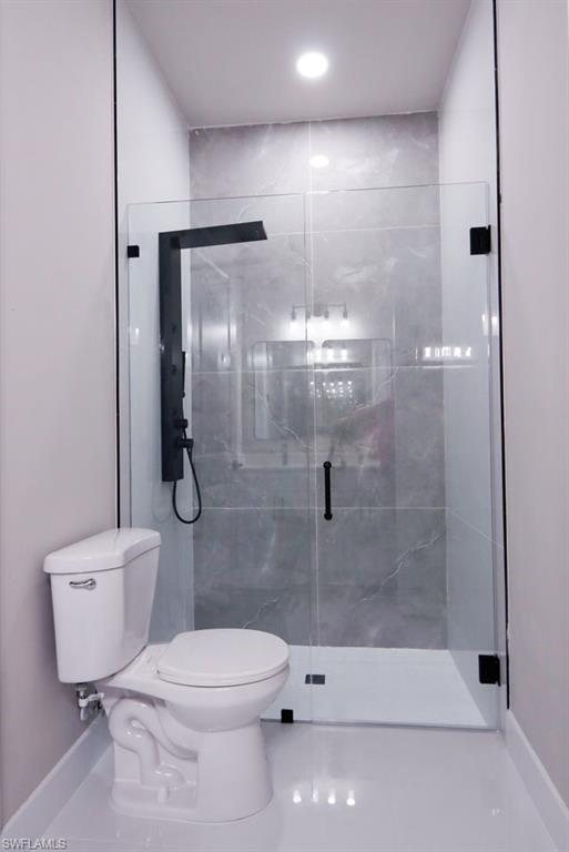 Bathroom featuring baseboards and a marble finish shower