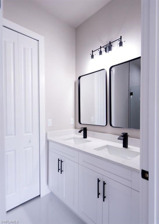 Full bathroom with double vanity and light tile patterned floors