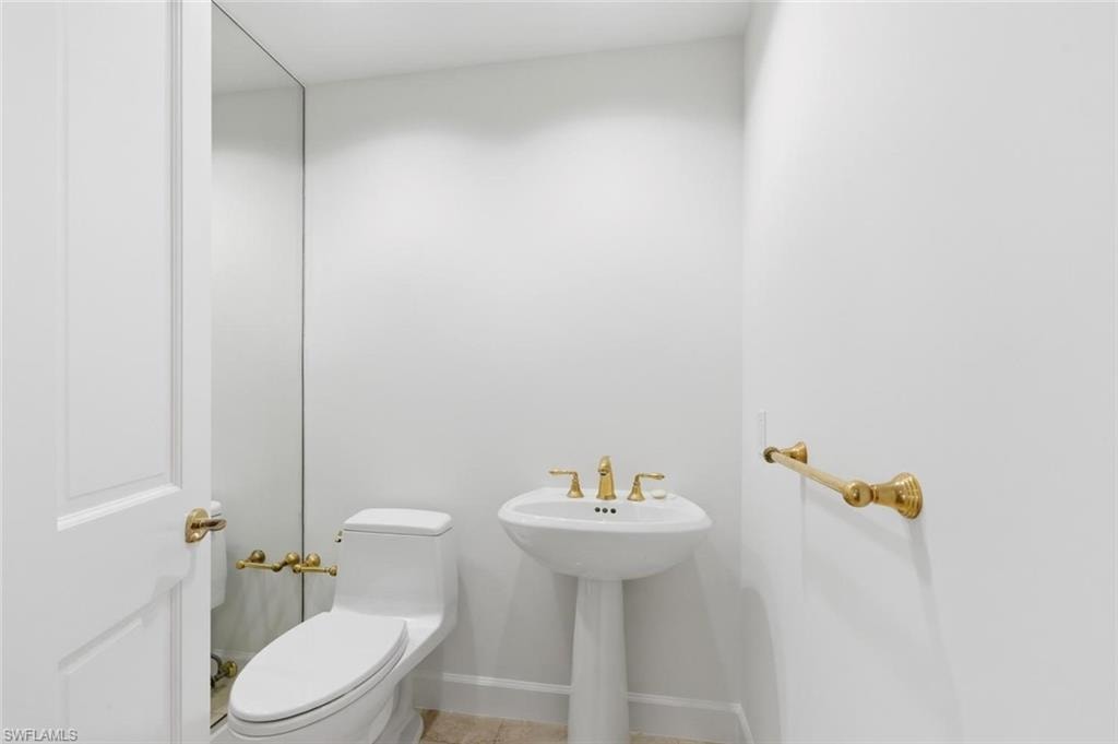 Pedestal sink with brass-finish faucet fixtures and coordinating towel bar