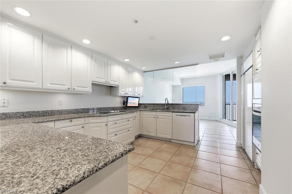 White cabinetry kitchen featuring speckled countertops, stainless steel appliances, recessed lighting, and tile flooring