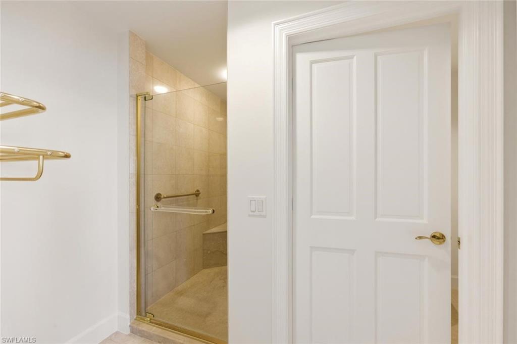 Enclosed shower with gold-toned frame, tiled walls, and integrated bench seating