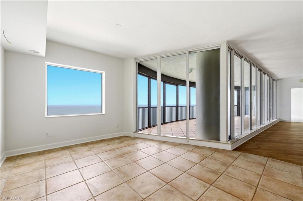 Spacious room with large-format tile flooring, a horizontal window, and a wall of sliding glass doors opening to a private balcony