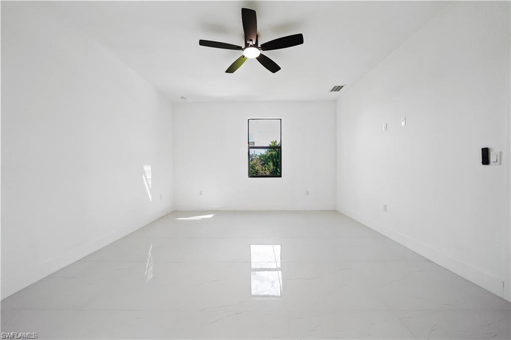 Empty room featuring ceiling fan and light marble finish floors
