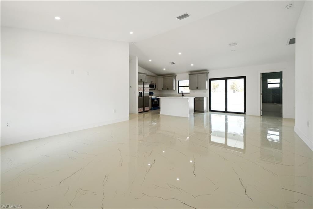 Spacious interior featuring pristine tile flooring, recessed lighting, and a kitchen with light-colored cabinetry and a large island
