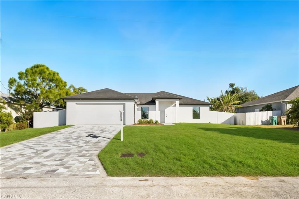 View of front of property with decorative driveway, stucco siding, and an attached garage
