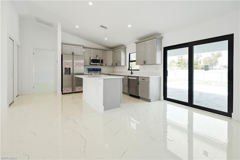 Modern kitchen featuring light gray cabinetry, stainless steel appliances, a center island, and white countertops