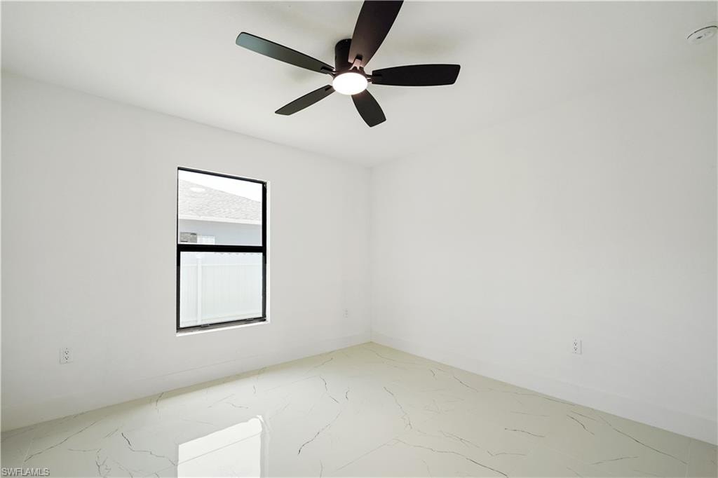 This space features a contemporary ceiling fan with a light fixture, a window providing natural light, and light-colored flooring with a subtle pattern