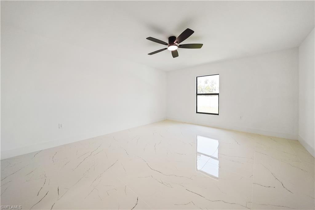 This room features bright white walls, a single window with a dark frame, and a ceiling fan with dark blades