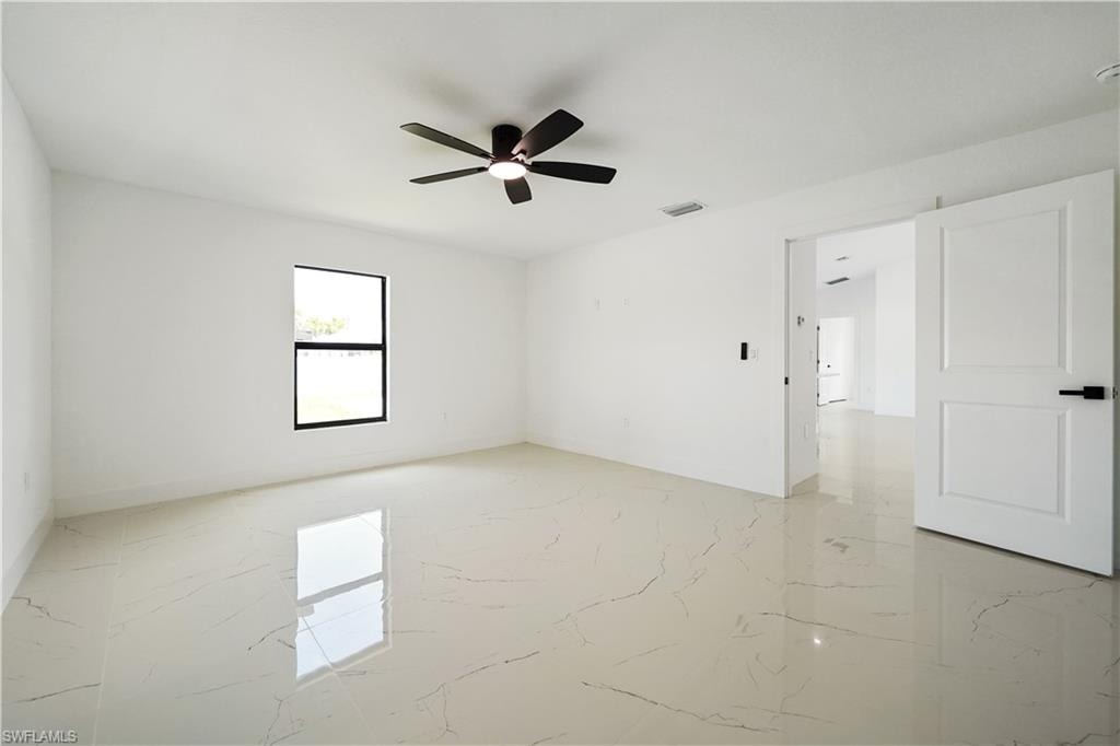 Spacious room featuring light-colored tile flooring, a ceiling fan, and a window providing natural light