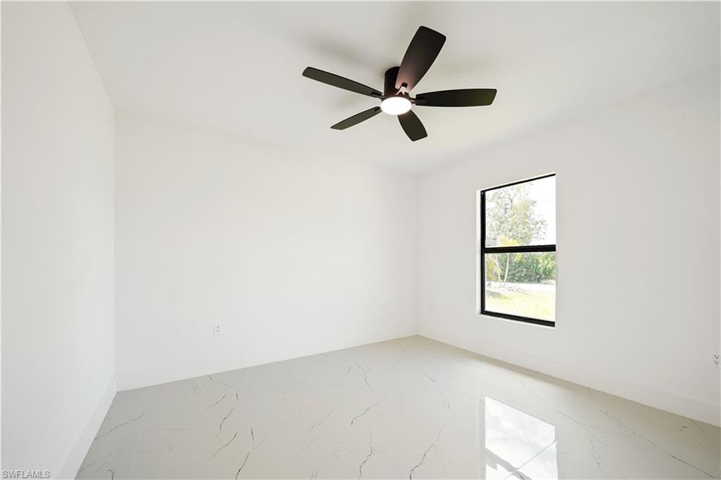 This room features a ceiling fan with integrated lighting, a window with dark framing, and light-colored tiled flooring