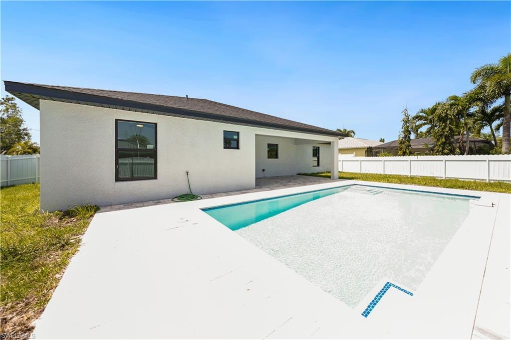 The property features a private swimming pool with a white tiled deck, a covered patio, and a white fence enclosing the yard