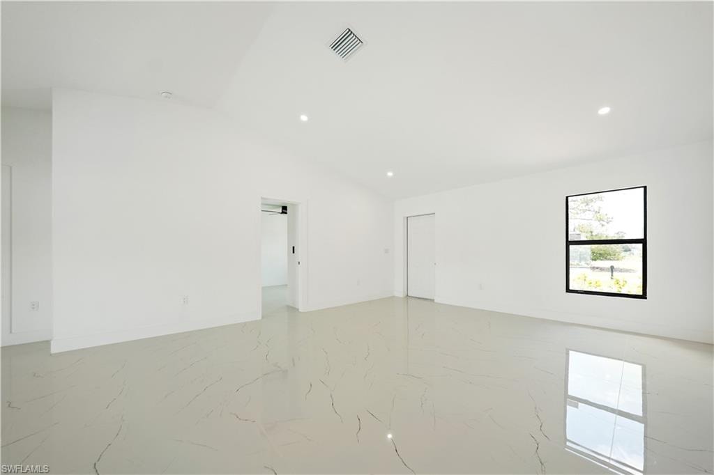 Spacious room featuring light-colored tile flooring, white walls, and recessed lighting