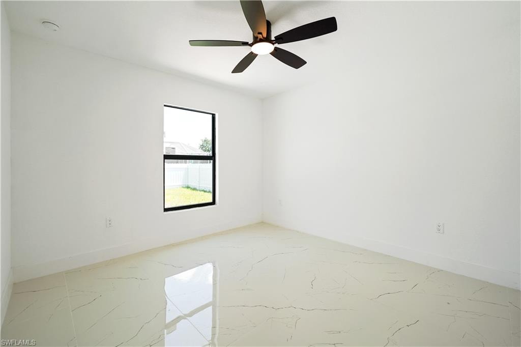This bright room features a contemporary ceiling fan, a window providing natural light and a view of the yard, and sleek tiled flooring