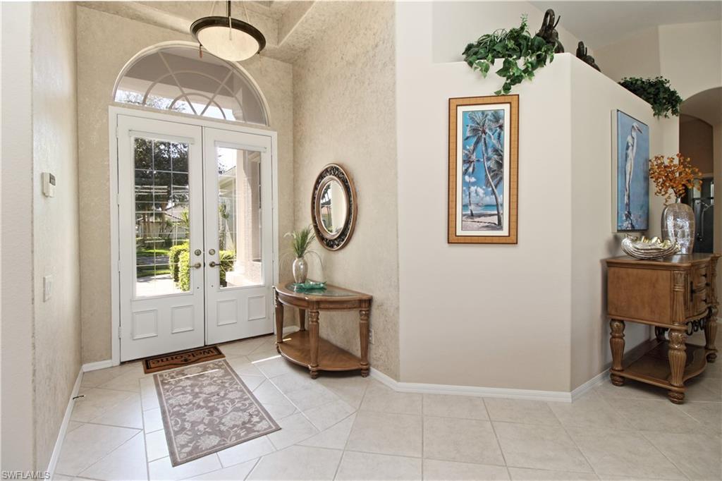 Entryway with light tile patterned floors, french doors, and arched walkways