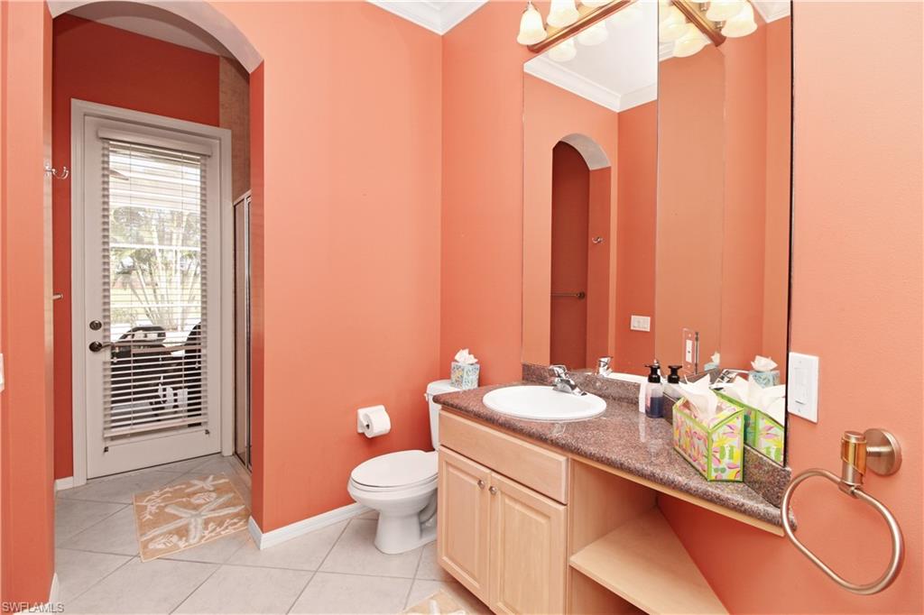 Full bathroom with a stall shower, vanity, light tile patterned floors, and crown molding