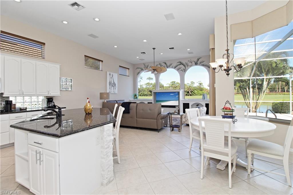 Kitchen featuring dark stone counters, white cabinetry, an island with sink, recessed lighting, and light tile patterned floors