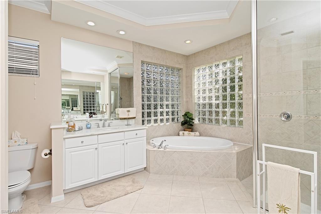 Full bathroom with ornamental molding, a stall shower, a garden tub, vanity, and light tile patterned floors