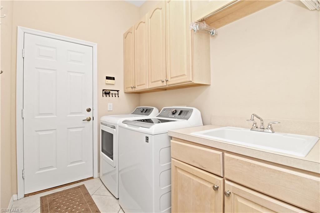Laundry room with cabinet space, washing machine and dryer, and light tile patterned floors