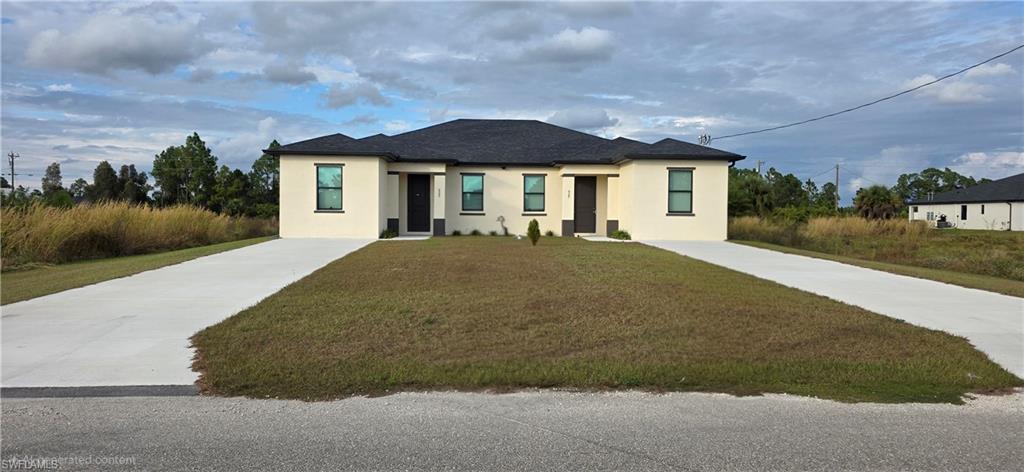 View of front of property with stucco siding, concrete driveway, and a front lawn