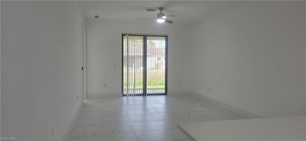 Unfurnished room with light marble finish floors and a ceiling fan
