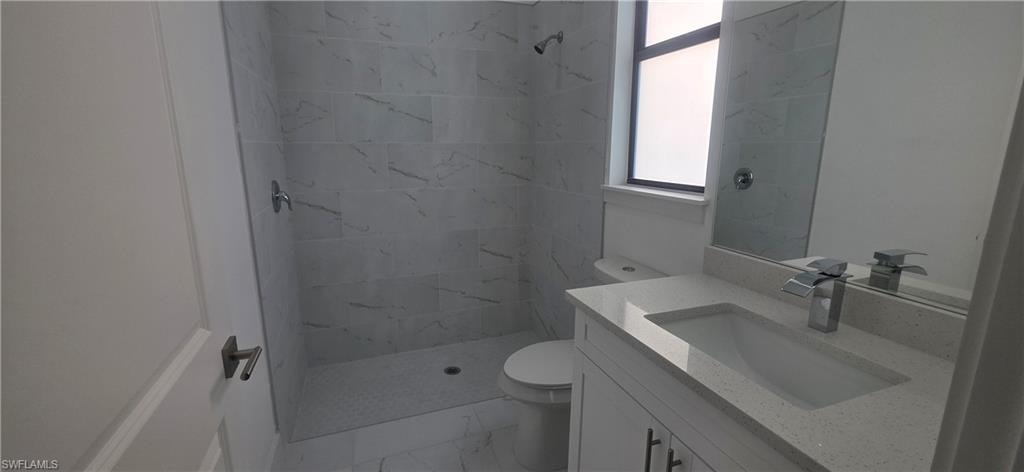 Bathroom with a marble finish shower, vanity, and light marble finish floors