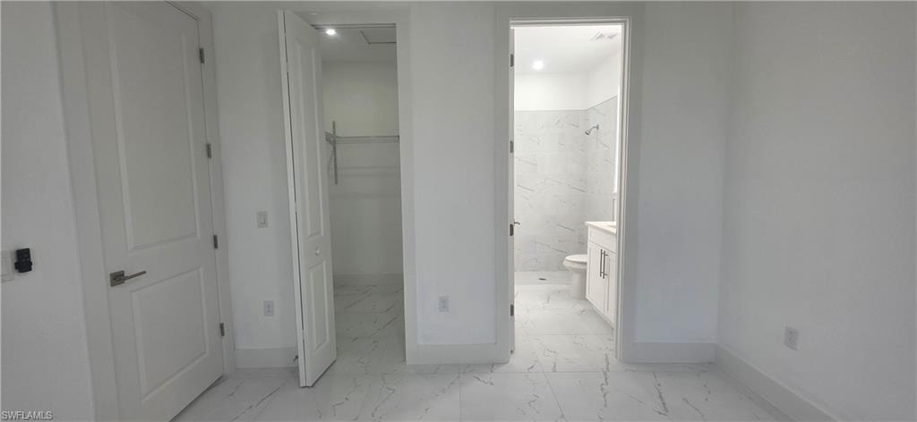 Full bathroom with light marble finish floors, a spacious closet, vanity, and a marble finish shower