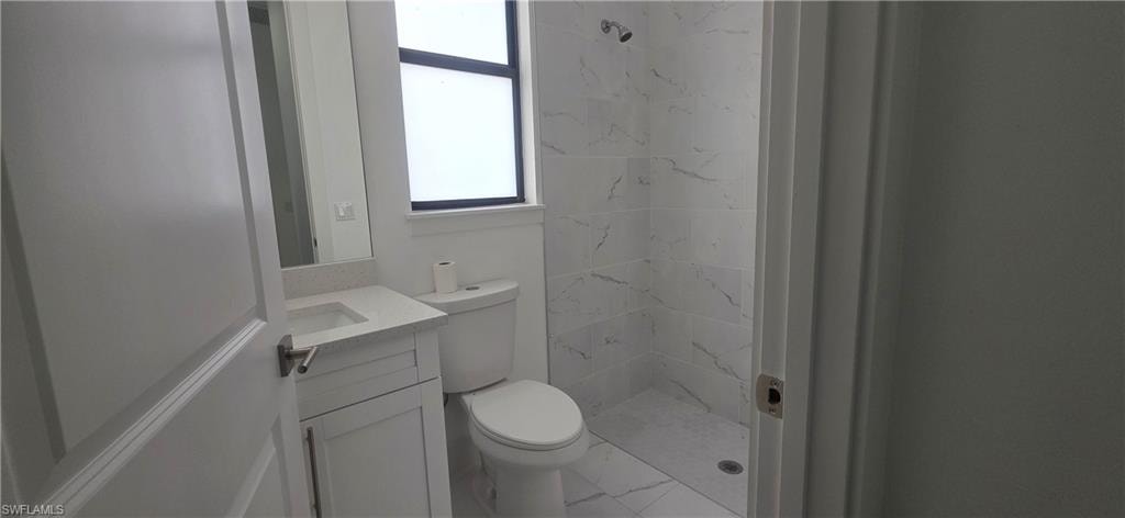 Full bathroom with a shower stall, vanity, and marble look tile flooring