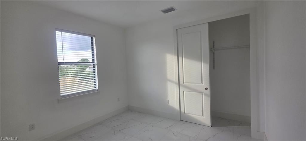 Unfurnished bedroom with a closet and light marble finish flooring