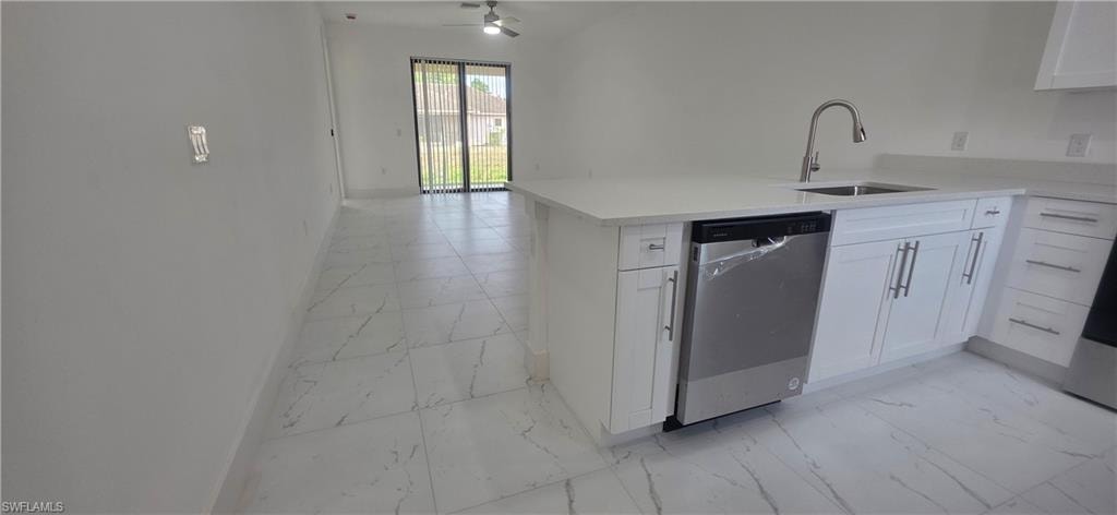 Kitchen featuring light marble finish flooring, stainless steel dishwasher, white cabinets, a peninsula, and light stone countertops