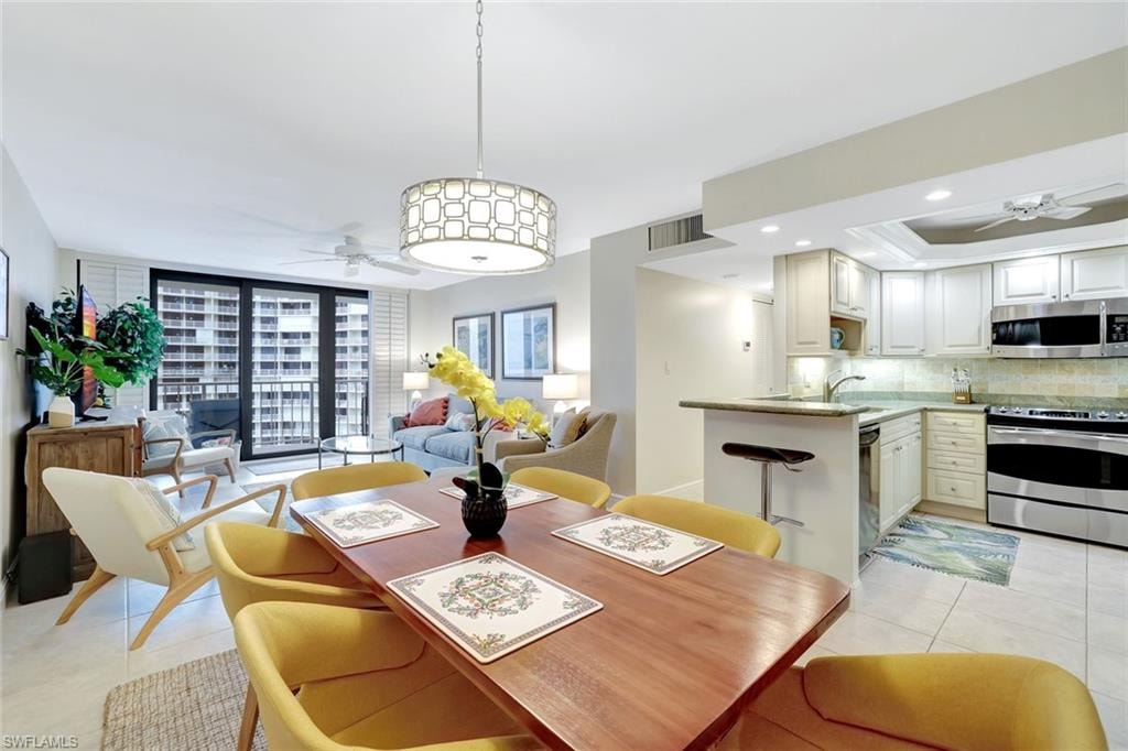 Dining space featuring ceiling fan, light tile patterned flooring, floor to ceiling windows, recessed lighting, and a raised ceiling